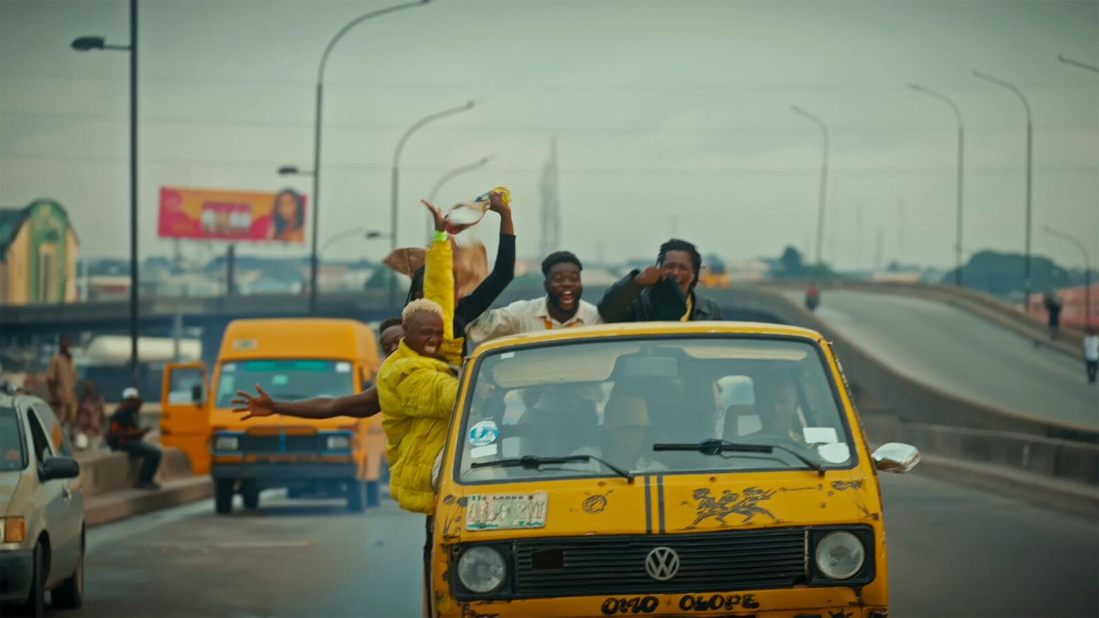 When Nigeria Happens. Fem personer står i en gul minibuss. Andre gule busser og biler er synlige på veien.