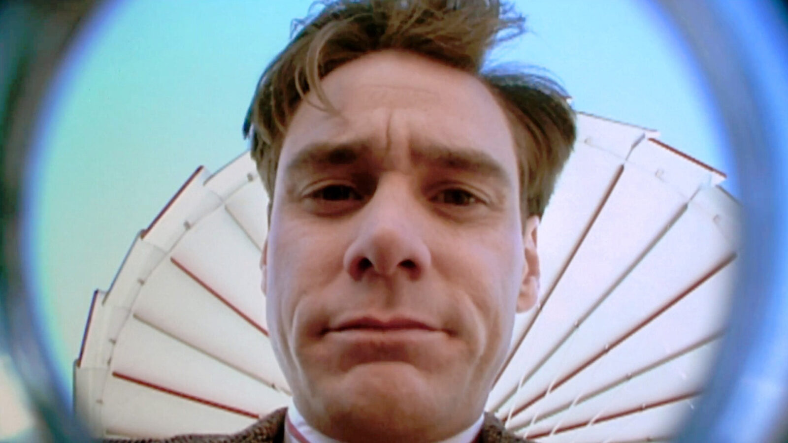The Truman Show En stor skjerm på en bygning viser et nærbilde av en mann som ligger med hodet på en pute Et helikopter og mange mennesker er synlige rundt bygningen