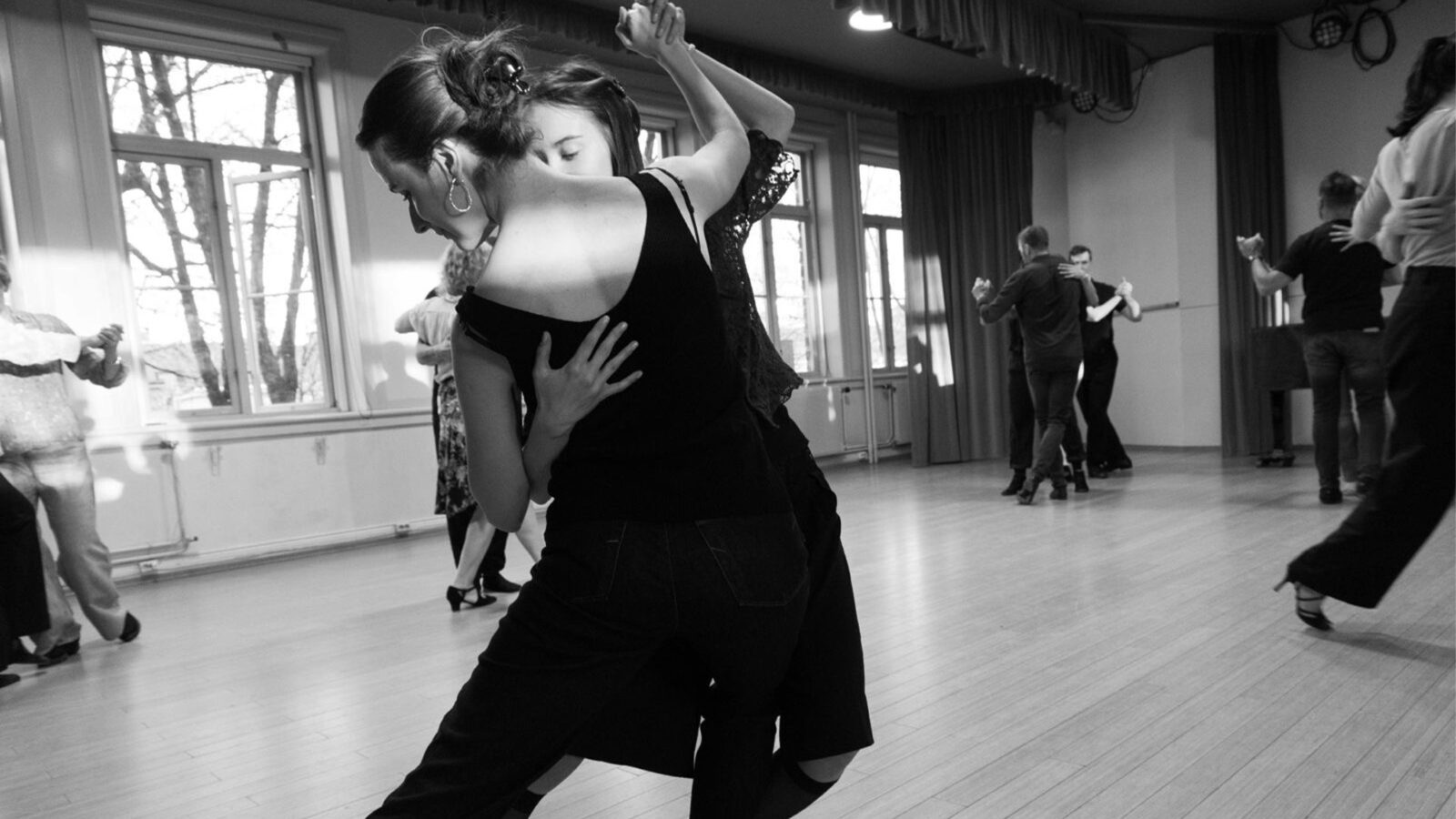 Milonga paa Lemongrass.  Flere par danser tett sammen i et lyst rom med store vinduer og gardiner