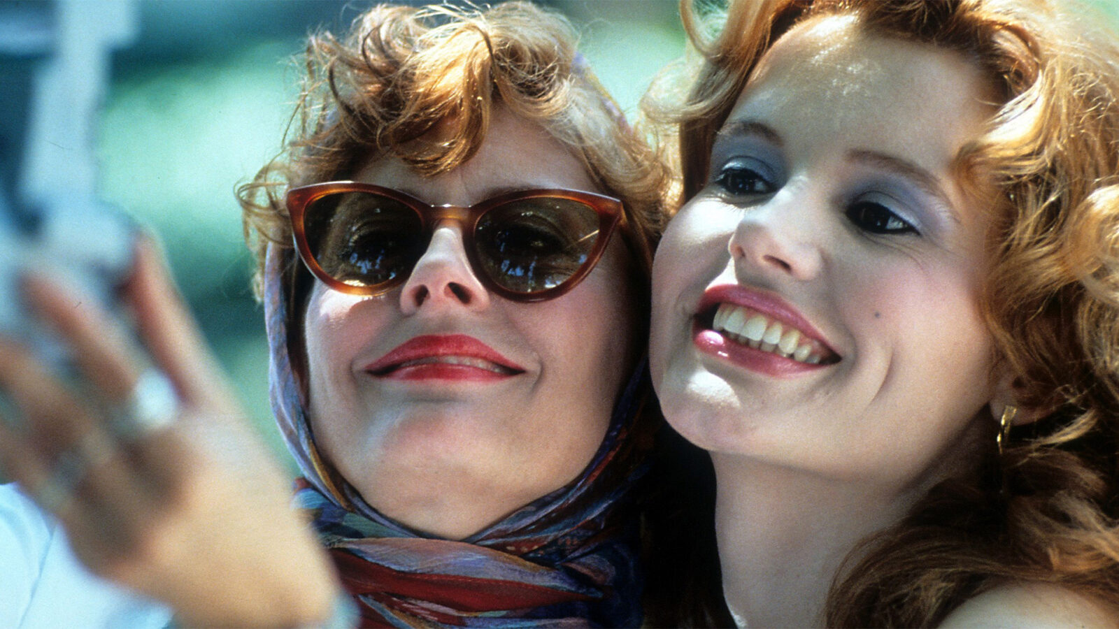 Thelma and Louise To kvinner med lyst hår tar et nærbilde sammen Den ene har solbriller og skjerf Begge smiler og ser mot kamera